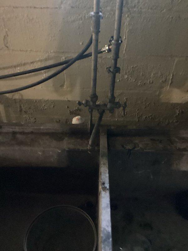 Completed routine plumbing inspection of basement utility area, examining vertical drainage lines, PVC piping system, and sump pump installation. All plumbing infrastructure, including brass valve connections and drainage components, were visually inspected and documented with photos for maintenance records.