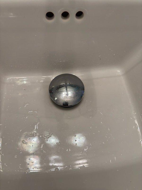 Replaced defective pop-up drain assembly in basement bathroom sink with new LUXIER 1-5/8 inch brass push pop-up drain stopper with overflow in chrome finish. Removed old pop-up assembly and installed new unit, ensuring proper seal and alignment. Performed leak test by running water for 10 minutes and filling sink basin five times to verify installation integrity. No leaks detected at drain connections or overflow assembly. Left fixture in full operational service.