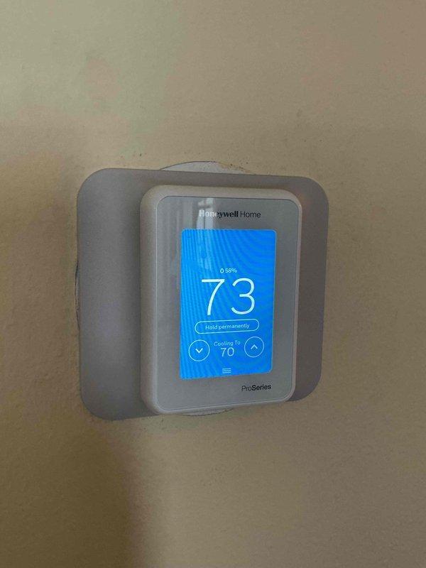 Responded to service call regarding excessive heat pump runtime and elevated winter utility costs. Upon inspection, discovered heat pump was configured to lock out at 40°F outdoor temperature, but outdoor sensor was receiving direct morning sunlight on east-facing unit, causing false temperature readings and preventing proper lockout during cold weather operation. Reconfigured Honeywell Home ProSeries thermostat to utilize internet-based outdoor temperature data instead of outdoor sensor input. Set up homeowner's mobile app connectivity for remote monitoring. Verified system cooling operation and confirmed proper thermostat functionality with new temperature source configuration. System now operating within normal parameters with corrected outdoor temperature reference.
