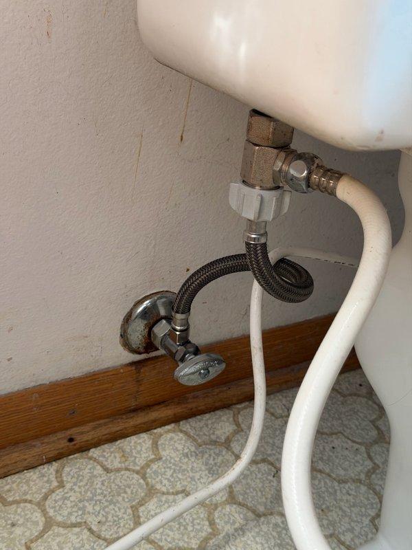 Responded to emergency plumbing call for toilet flooding issue caused by failed wax ring seal and defective water supply connections. Main water supply was shut off upon arrival due to uncontrollable flooding when turned on, as the toilet's individual shut-off valve was inoperable and missing its handle. Removed and reset toilet after discovering deteriorated wax ring causing leak at floor flange connection. Replaced old angle stop valve with new unit featuring proper shutoff handle for future maintenance access. Repaired compression fitting on water supply line and installed new braided stainless steel flexible supply line to ensure secure, leak-free connection between angle stop and toilet tank fill valve. Tested all connections under full water pressure to confirm proper operation and verified no leaks at wax ring seal, angle stop valve, or supply line connections.