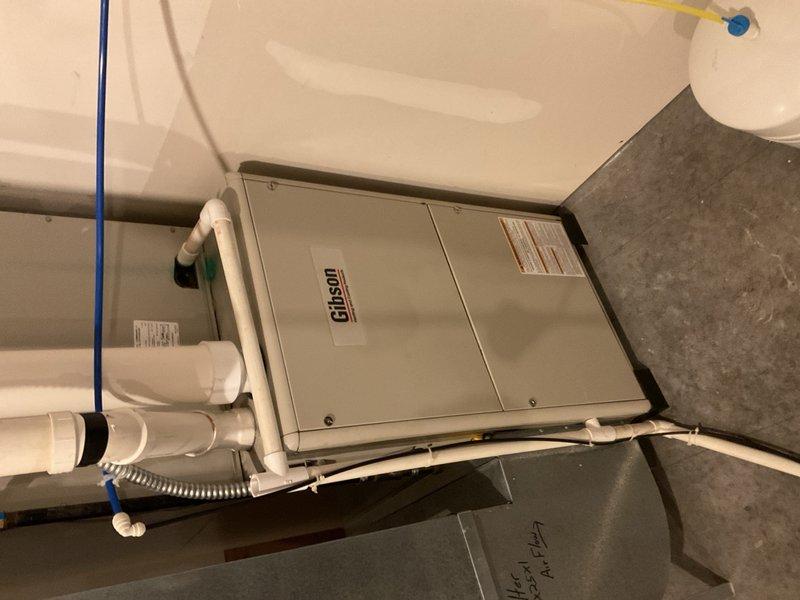 Performed cooling maintenance on a 2019 Nordyne split AC system with furnace serving a 5,000 sq ft home. Found the outdoor condenser coil heavily impacted with debris, restricting heat rejection and contributing to hot liquid line temperatures and elevated electric usage. Cleaned condenser coil to restore proper heat transfer efficiency. Indoor inspection revealed a 100,000 BTU furnace with PSC blower motor and undersized 16x25x1 filter arrangement for home size, which may be contributing to airflow restriction and increased operating costs. Observed water beneath blower housing and performed camera inspection of evaporator coil and drain pan. Removed delta plate and flushed approximately 1 gallon of water through condensate pan; primary drain system passed water successfully. Further investigation identified moisture source as condensation and water intrusion from PVC combustion air intake pipe, which was dripping onto gas valve, inducer assembly, and burner deck before migrating to b