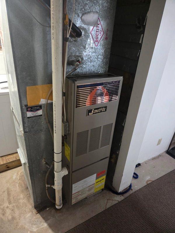 Responded to no cooling complaint on 33-year-old R22 system experiencing coil freeze-up. Upon arrival, diagnosed low refrigerant charge as primary cause of icing condition. During inspection, identified signs of low-level carbon monoxide leakage from furnace burner compartment front cover. Advised system shutdown and fan-only operation to allow complete defrost of evaporator coil prior to service. Documented equipment condition with photographs showing Janitrol Ninety-Plus furnace installation and overall system age. Due to obsolete R22 refrigerant, advanced system age exceeding service life expectancy, and safety concerns with carbon monoxide detection, recommended comfort advisor consultation for system replacement options.