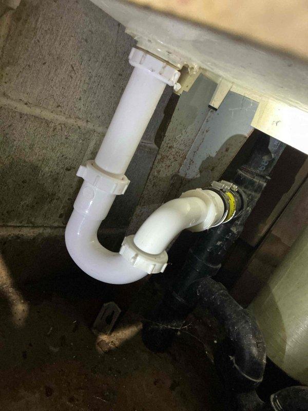 Responded to service call for broken laundry tub trap and main line drainage issue. Upon arrival, diagnosed that the existing trap assembly had failed and the laundry drain line was clogged and not flowing properly.

Cabled the laundry drain line to clear the obstruction, successfully restoring proper drainage and flow. Removed the deteriorated trap 90 assembly from the laundry tub and installed a new white PVC tubular P-trap configuration to code specifications. Secured all connections and verified proper sealing at all joints.

Tested the complete drainage system for proper operation and confirmed all fixtures were draining correctly with no leaks present. During inspection, noted that the floor drain float valve was no longer functioning as designed but determined it was not restricting drainage flow at this time. Observed significant corrosion on the main water shut-off valve assembly and provided verbal estimate for future replacement, though no work was authorized at this time. A
