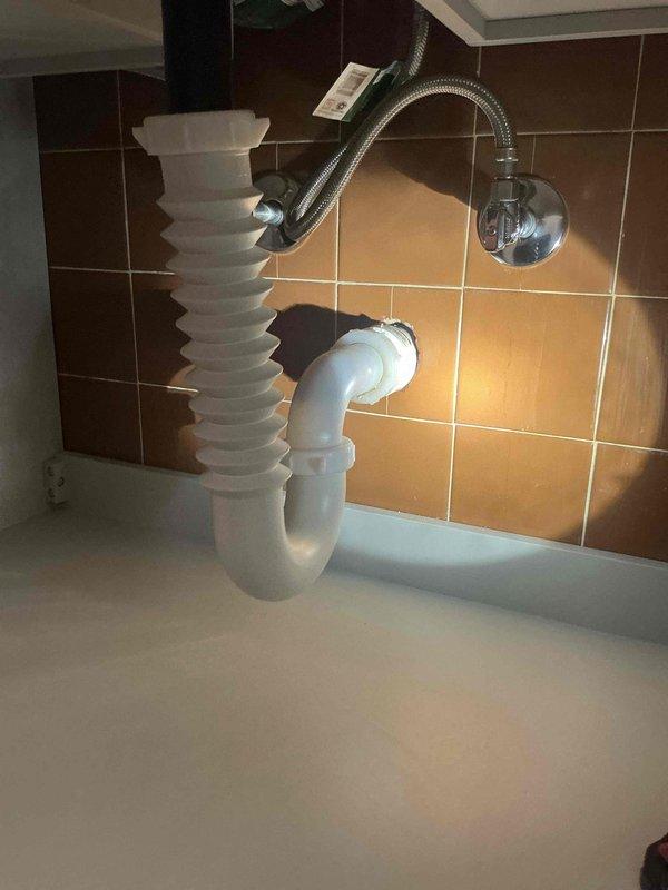 Replaced non-compliant accordion-style drain trap with code-approved PVC P-trap assembly and extension tailpiece. Installation completed to meet inspection requirements, with all connections properly secured and tested for leaks.