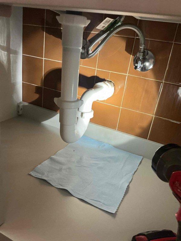 Replaced non-compliant accordion-style drain trap with code-approved PVC P-trap assembly and extension tailpiece. Installation completed to meet inspection requirements, with all connections properly secured and tested for leaks.