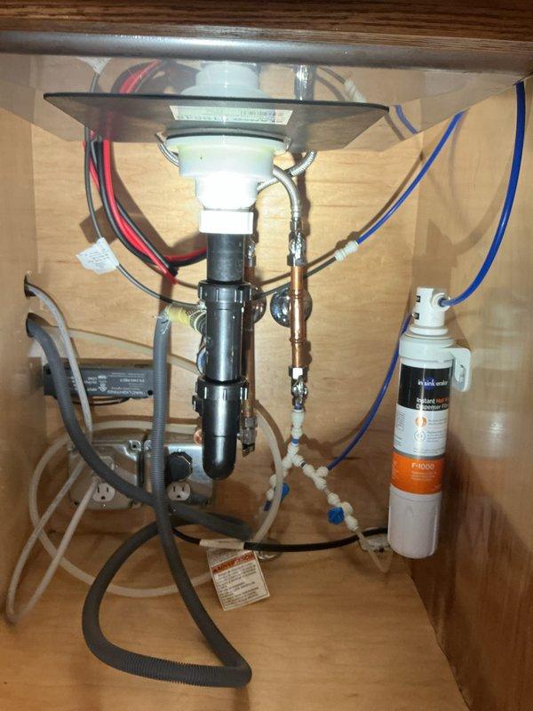 Completed installation of kitchen faucet and filtered drinking water faucet system. All connections were properly secured to existing plumbing infrastructure, including integration with garbage disposal unit, supply lines, and water filtration system with visible filter cartridge mounted in cabinet space.