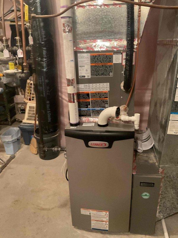 Responded to water leak at Lennox furnace caused by improperly installed condensate drainage system. Found PVC tee fitting at rear of furnace was not glued during original installation, resulting in active water leakage. Properly cleaned and glued PVC connection at tee fitting, reconnected high voltage power to furnace and air conditioning system, and verified system operation with no further leaks detected.