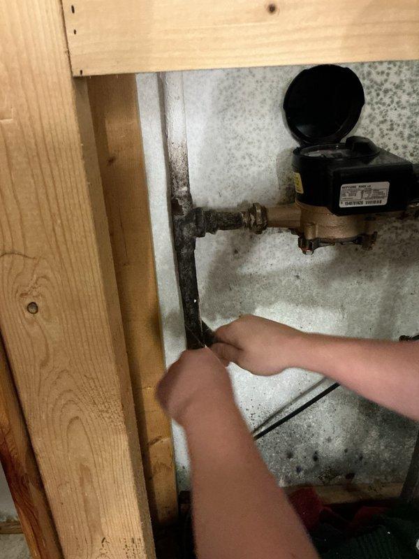 Responded to a water leak at the water meter location with visible spraying on surrounding walls and potential mold concerns. Upon inspection, identified the leak originating from the water meter housing itself. Discovered the property lacked a shut-off valve after the meter, which is necessary for future service and emergency situations. Installed a new brass valve immediately downstream of the meter to provide proper isolation capability. Coordinated with municipal water department for meter replacement due to housing failure. Municipal technician arrived on-site and successfully replaced the defective water meter while we remained to ensure proper completion and verify no additional leaks at connections. All plumbing connections secured and tested. System restored to full operational status with improved serviceability.
