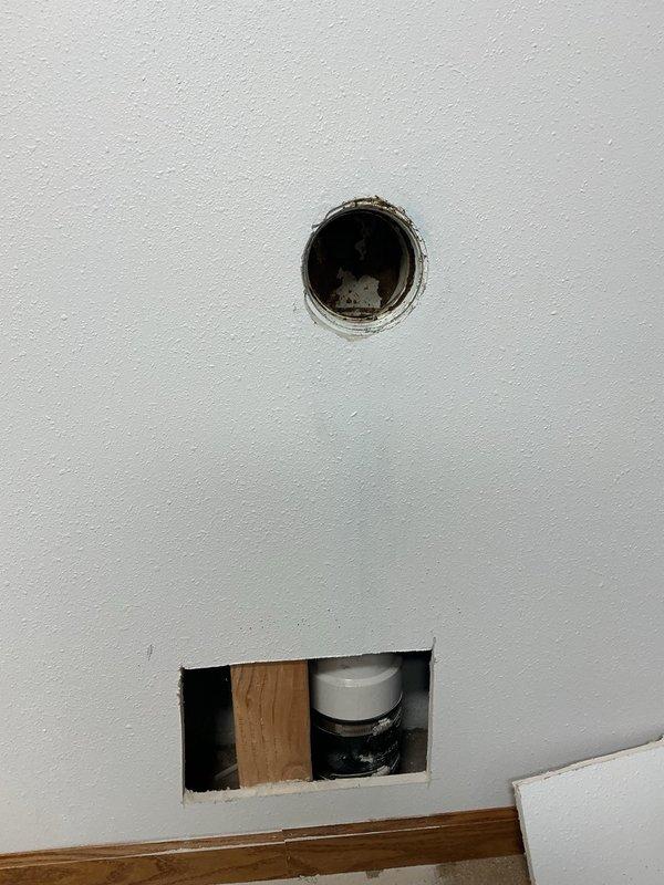 Responded to a main line sewer blockage in a 4-inch drain pipe. Attempted to clear the obstruction using both snake and camera equipment, but encountered an impenetrable blockage immediately after the 90-degree elbow fitting where the line enters the ground beneath the floor. Diagnostic inspection indicates a probable pipe compromise, either a collapse or significant breach in the line under the concrete slab. Created access points in the wall to expose the plumbing system for assessment. Documented conditions with photographic evidence showing the compromised drain line and utility area. Consulted with property owner regarding the severity of the issue and recommended floor excavation to access and repair the damaged section of pipe.