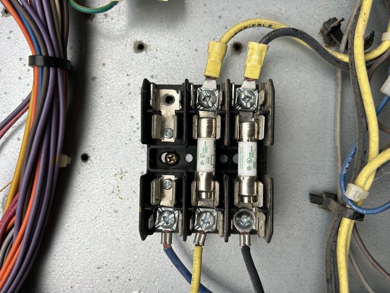 Responded to no cooling complaint on three RTU units at commercial facility with approximately 12 total rooftop units. Initial diagnostic visit was shortened due to inclement weather conditions. On Unit 16 serving the welding room, identified one failed compressor that customer elected not to repair, and discovered condenser fan motors inoperative—traced issue to blown fuses requiring replacement on return visit. Confirmed cracked heat exchanger on second unit, which customer has chosen not to repair due to pending lease expiration. Third unit requires additional diagnostics to be completed on scheduled return trip. Documented electrical components and fuse assembly with photos for reference. Return visit needed to install fuses, restore condenser fan operation on Unit 16, and complete diagnostics on remaining non-cooling unit.