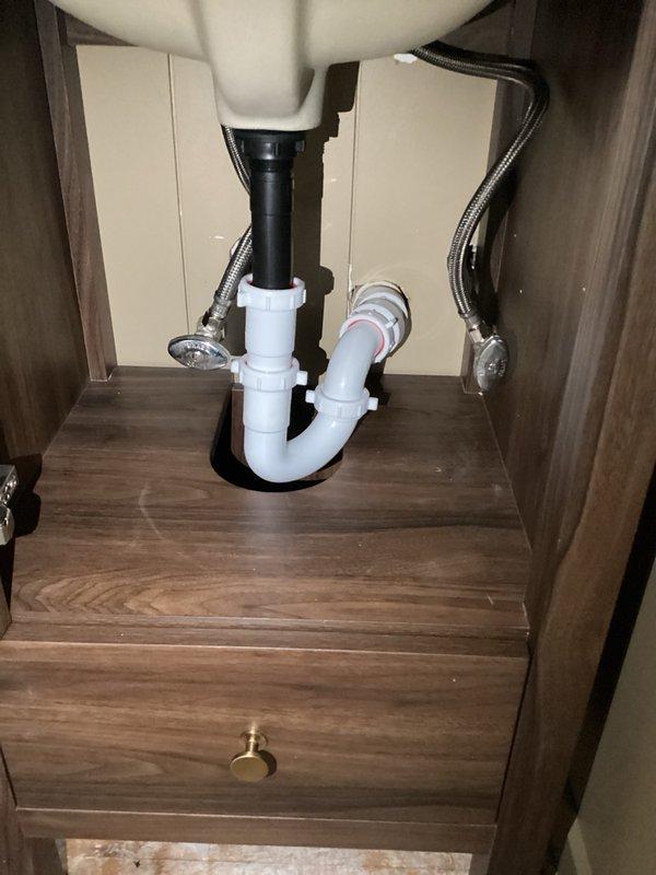 Installed homeowner-supplied bathroom lavatory faucet with hot and cold water supply connections. Connected braided stainless steel supply lines to shutoff valves and secured faucet assembly to sink basin. Installed white PVC P-trap drain assembly and waste connections, ensuring proper drainage and trap configuration to prevent sewer gas infiltration. All connections tested and verified leak-free upon completion.