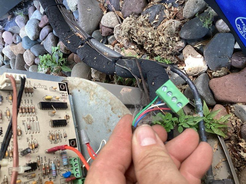 Responded to no cooling call on 15-year-old Carrier Infinity communicating air conditioning system. Found condenser unit non-operational with extensive rodent damage to wiring and control board, along with significant debris accumulation throughout the unit interior. Cleared rodent nesting material and organic debris from condenser cabinet. Repaired damaged wiring harness and verified 24V present at four-wire communication plug. Upon testing, system powered on briefly but immediately shut down with utility company energy saver switch displaying blinking green indicator light. Reset energy management device multiple times with same result, indicating failure of utility-owned load control equipment. Confirmed all customer-owned equipment wiring repairs successful and system capable of operation once utility device issue resolved. Recommended contacting utility company for service on malfunctioning energy saver switch to restore normal system operation.