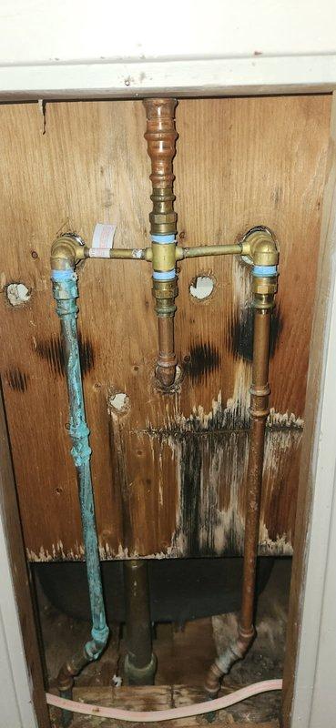 Responded to a water leak complaint originating from a tub faucet spraying behind the wall. Accessed the plumbing through an adjacent room opening, where inspection revealed significant water damage to the wooden back panel with extensive dark staining and moisture accumulation, indicating prolonged leakage from the deteriorated tub faucet assembly. The existing two-handle tub faucet without shower capability required replacement. Documented the condition of the plumbing installation, including corroded supply lines and damaged surrounding materials. Provided an estimate for replacing the widespread tub faucet and scheduled a follow-up appointment to present additional options for installing a complete tub and shower surround system with integrated showerhead functionality.