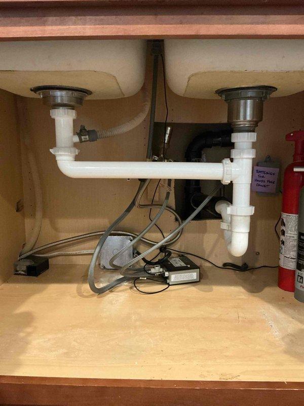 Responded to a kitchen sink backup affecting multiple fixtures in the residence. Upon diagnostic testing, identified a blockage in the shared basement drain line that caused water to back up within 30 seconds of operation. Cabled the basement sink drain to approximately 20 feet using mechanical drain cleaning equipment and successfully cleared the obstruction, which appeared to be dental floss material. Tested the drain system by running water for 10 minutes to confirm proper flow with no backup or leaks detected.

Removed the existing garbage disposal unit, which was infrequently used and producing odors. Installed a new basket strainer assembly with end waste connection to replace the disposal. Connected all drain components using appropriate PVC fittings and verified secure connections. Conducted thorough operational testing of the entire drainage system to ensure proper function and confirm no leaks were present at any connection points.

As an additional courtesy, resealed the bas