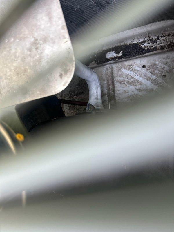 Responded to no cooling complaint on a 20-year-old air conditioning system experiencing frequent freeze-ups. Upon inspection, found unit severely low on R22 refrigerant and identified missing insulation on refrigerant lines where frost and ice had been accumulating. System manufactured in 1988 per nameplate data (Model CA50300KA1). Due to age of equipment, obsolete R22 refrigerant requirements, and ongoing refrigerant loss indicating likely leak in system, recommended complete air conditioning replacement rather than repair. Documented equipment condition and refrigerant deficiency with photos showing manufacturer specifications and evaporator coil area with dust accumulation. Customer advised that continued repairs would not be cost-effective given system age and refrigerant phase-out.