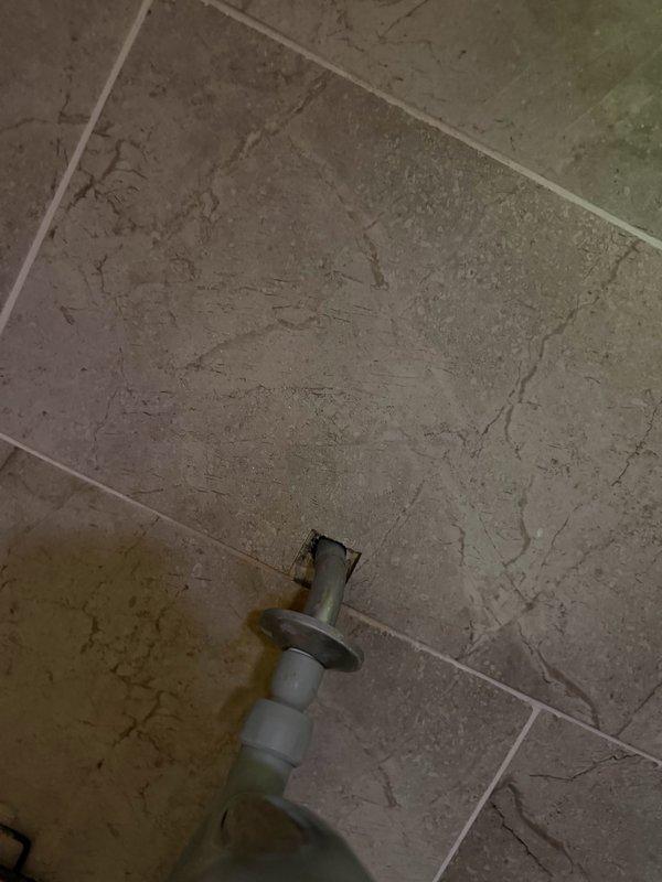 Responded to water leak originating from master bathroom shower affecting basement drop ceiling below. Upon investigation, identified shower head was spraying backwards toward wall, allowing water infiltration behind the escutcheon plate and subsequently running down interior drywall. Removed defective shower head and installed new replacement unit. Applied silicone sealant behind escutcheon to create proper water barrier and prevent future moisture penetration into wall cavity.