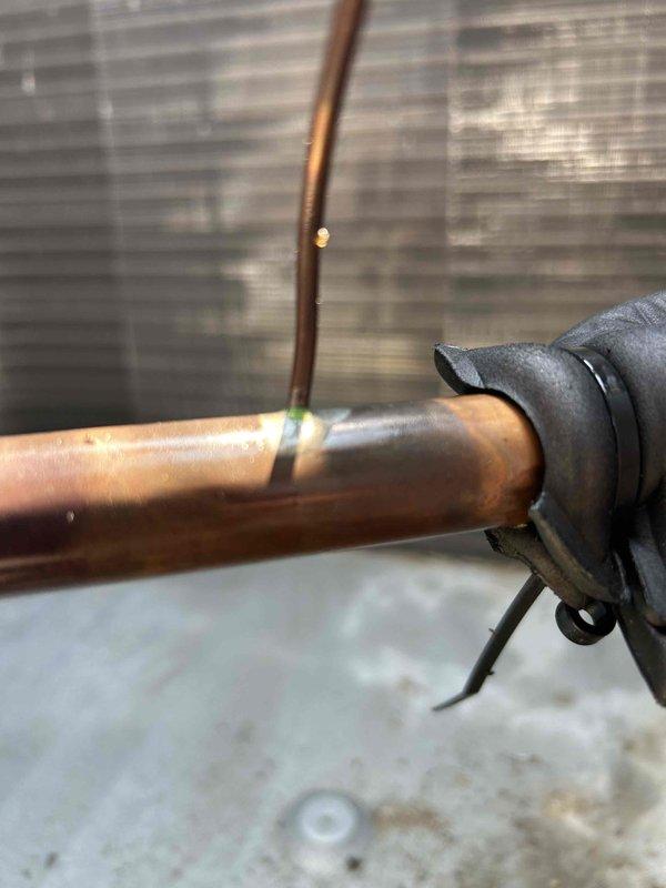 Responded to no cooling call for commercial building with multiple RTU failures. Northwest rooftop unit was tripped on high head pressure; reset unit and rinsed condenser coils on both westside units with water, restoring operation. Kitchen RTU compressor #1 found completely flat on refrigerant charge with evidence of previous refrigerant fills and dye testing. Located significant oil accumulation at TXV suction line connection point indicating cracked fitting and active refrigerant leak. Documented findings and submitted part order form for leak repair quote.
