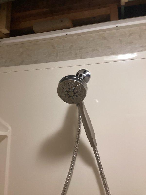 Installed customer-supplied handheld shower head assembly in residential bathroom shower enclosure. Secured chrome-finish shower head unit to existing wall bracket and verified proper connection of flexible stainless steel braided hose to water supply. Tested fixture operation to ensure leak-free installation and proper water flow through spray nozzles.