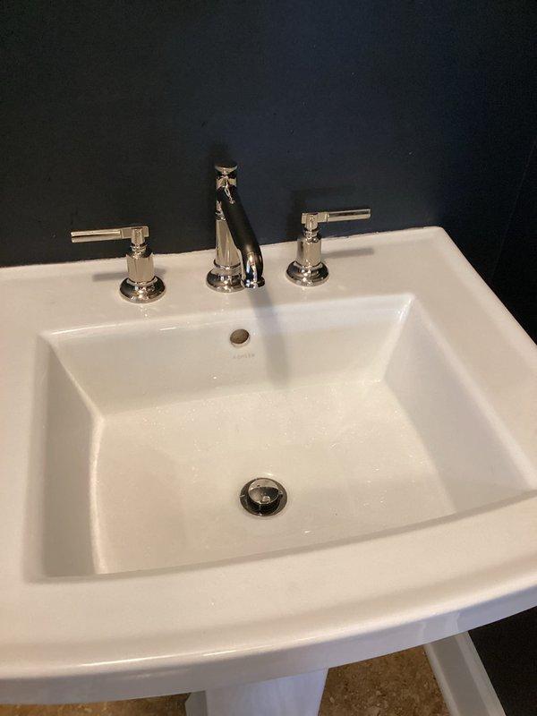 Installed new widespread bathroom faucet with three-hole configuration on existing white ceramic sink basin. Connected braided stainless steel supply lines to angle stop valves and secured all plumbing connections beneath fixture, ensuring proper water flow and leak-free operation.