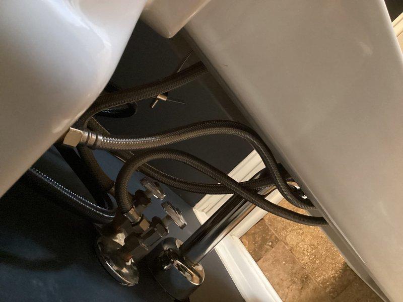 Installed new widespread bathroom faucet with three-hole configuration on existing white ceramic sink basin. Connected braided stainless steel supply lines to angle stop valves and secured all plumbing connections beneath fixture, ensuring proper water flow and leak-free operation.