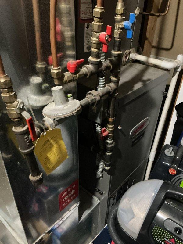 Responded to no cooling complaint on 17-year-old air conditioning system blowing warm air. Upon arrival, found system not running with low pressure switch tripped due to low refrigerant charge. Temporarily bypassed low pressure switch to verify system operation and confirm refrigerant leak in system. Diagnosed refrigerant loss requiring leak search and repair. Documented equipment condition with photos of mechanical room showing water heater, HVAC components, and piping configuration, as well as unit nameplate information. Provided customer with repair options including refrigerant recharge, leak detection and repair, or full system replacement given age of equipment. Scheduled same-day estimate appointment for new air conditioning system replacement.
