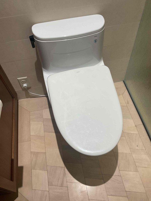 Responded to service call for loose toilet seat. Upon inspection, found toilet seat hardware had loosened, causing instability. Tightened existing mounting bolts and hardware to secure seat properly. Submitted parts request form for potential oval-shaped white replacement seat if future replacement becomes necessary.