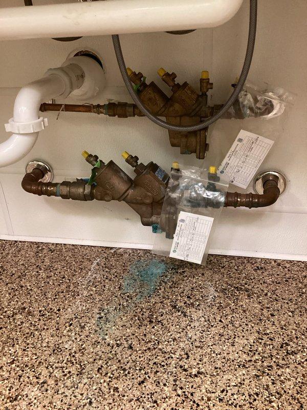 Responded to callback for continuously leaking backflow prevention system affecting entire building with water hammer, spitting, and hissing sounds. Diagnosed air infiltration into hot water system originating from failed recirculation pump. Inspected dual RPZ backflow assemblies showing significant age-related corrosion and deterioration, along with damaged recirculation pump assembly exhibiting active leakage at connection points. Provided estimate for recirculation pump repair to resolve building-wide water system issues.