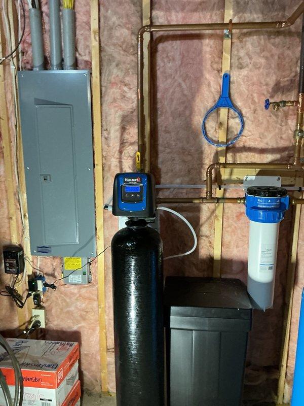 Completed comprehensive plumbing inspection of residential property. Inspected water treatment system including softener tank, filtration unit with digital control head, and associated copper piping connections in basement utility area. Evaluated bathroom fixtures including tub/shower assembly with chrome hardware and identified toilet components requiring replacement due to wear and deterioration.