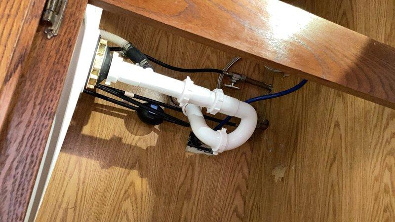 Responded to kitchen sink leak located under the cabinet. Upon inspection, discovered the P-trap O-rings were installed backwards, causing water seepage. Removed the existing trap assembly and replaced the complete under-sink drainage system with new PVC components. Installed proper P-trap configuration with correctly oriented O-rings to ensure watertight seal. Additionally, installed new dishwasher drain connection and tailpiece assembly to accommodate dishwasher hookup as requested. Secured all connections, tested system for leaks, and verified proper drainage flow. All work completed successfully with no active leaks detected.