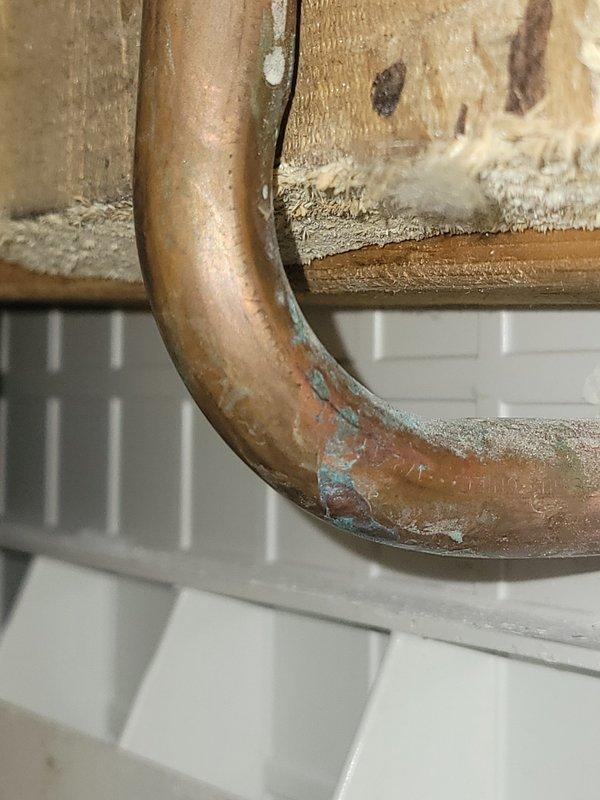 Responded to water line break in bathroom shower system. Upon inspection, identified cracked copper tub spout arm at the bend joint, which had developed a failure point causing active water leakage. Created wall access opening to expose the plumbing assembly and assess the full extent of the damage. The copper pipe exhibited significant corrosion and oxidation, particularly concentrated at the U-bend section where the crack had formed. Removed the damaged tub spout arm and installed a replacement component. Verified all connections for proper seal and tested the system under full water pressure to confirm leak resolution and restore normal operation.