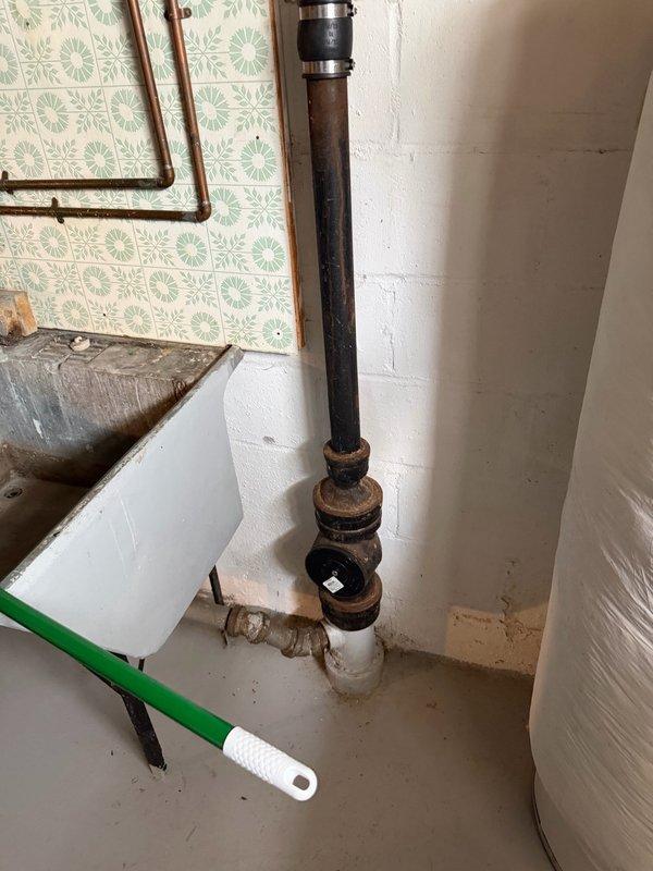Completed comprehensive plumbing inspection of residential property with focus on aging water supply lines and drain systems. Documented extensive corrosion on vertical black iron drain pipe assembly and copper supply lines in utility area, noting visible rust on metal fittings and deterioration at connection points. Identified corroded trap assembly beneath floor with significant green patina indicating advanced oxidation of brass/copper components, along with evidence of moisture exposure and water staining on surrounding wood subflooring at pipe penetration points. Mixed plumbing materials observed throughout system including older metal components and newer white PVC sections connected via adapters, suggesting previous repair attempts. Provided detailed photographic documentation of all corroded components, leaking water lines, and areas requiring immediate attention. Prepared comprehensive estimate for necessary repairs to address active water line leaks and recommend replacement 