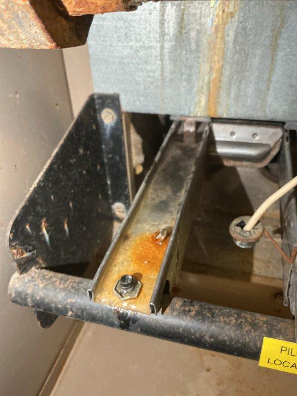 Responded to service call for water intrusion into furnace during rain events. Upon inspection, identified damaged or missing vent cap on furnace flue stack allowing water penetration through vent system. Documented extensive rust staining and corrosion on furnace components, including blower housing panel and internal framework, indicating ongoing moisture exposure. Photographed water damage patterns and deteriorated metal surfaces throughout unit. Recommended roofing contractor for vent cap repair or replacement to resolve water infiltration issue at source.