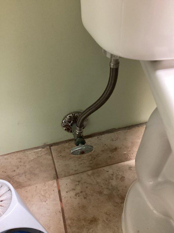 Responded to emergency call for leaking toilet causing water to flow into hallway at commercial office building. Upon arrival, building occupants had already shut off water supply to prevent further damage. Diagnosed failed toilet supply line as source of leak. Removed defective braided flexible supply line and installed new replacement, restoring proper connection between wall-mounted shut-off valve and toilet tank inlet. Verified all connections were secure, turned water supply back on, and tested system to confirm leak was eliminated and toilet was functioning properly.