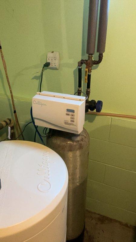Responded to service call for malfunctioning Culligan water softener system with reported issues of salt tank not consuming salt and irregular cycling patterns. Upon diagnostic inspection, determined that either the control head motherboard or the complete head assembly had failed, preventing proper system operation. Documented existing installation with wall-mounted electronic control unit, copper supply lines with brass fittings and shutoff valves, and white cylindrical brine tank. Provided customer with repair options including replacement of the control head assembly or installation of a complete new water softener system, with recommendation for follow-up estimate consultation.