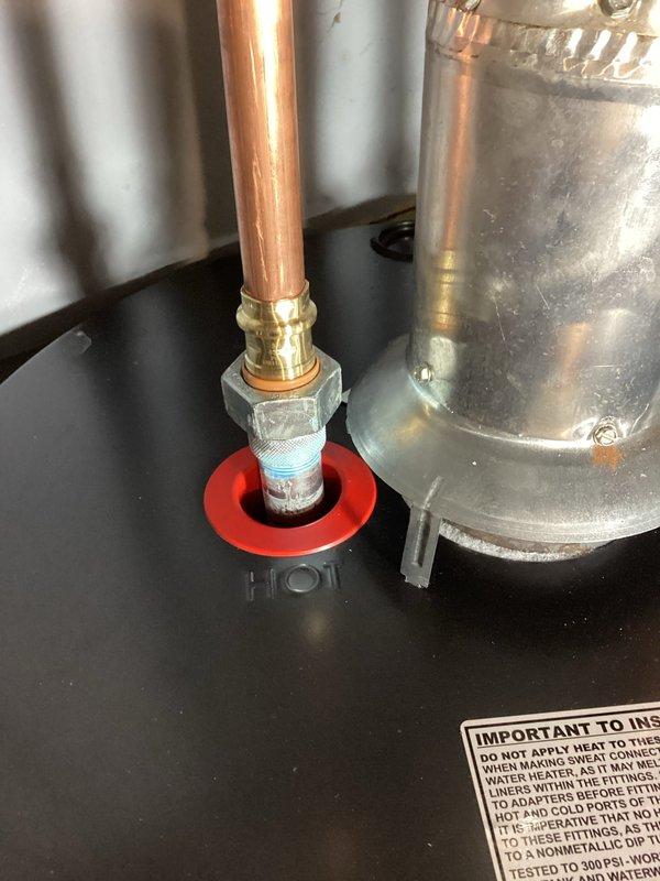 Responded to service call for reported leak at water heater. Upon inspection, identified leak originating from the hot water outlet dielectric union connection at top of tank. Tightened the dielectric union fitting to stop the leak and cleaned up accumulated water from the unit and surrounding area. Verified repair was successful with no further leakage observed. Documented repair with photographs of the affected plumbing connections and overall water heater installation.