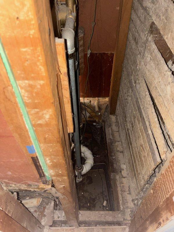 Responded to emergency water leak originating from upstairs bathroom shower valve, which was actively leaking through ceiling into lower level. Upon arrival, main water supply had been shut off to stop active leak. Accessed shower valve through existing access panel and confirmed leak at valve body, noting evidence of previous repair attempt. Inspected plumbing infrastructure in basement crawl space and utility chase, documenting pipe routing, drainage assembly, and overall system configuration with photographs. Discussed repair options with homeowner, who recently purchased property three weeks prior. Homeowner requested installation of isolation valves on bathroom plumbing group to allow localized water shutoff; however, inspection revealed water supply pipes in basement appear to have potential asbestos-containing insulation wrap, preventing immediate valve installation work. Homeowner elected to postpone all repairs pending consultation with legal counsel and real estate representa