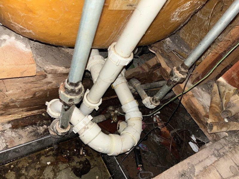 Responded to emergency water leak originating from upstairs bathroom shower valve, which was actively leaking through ceiling into lower level. Upon arrival, main water supply had been shut off to stop active leak. Accessed shower valve through existing access panel and confirmed leak at valve body, noting evidence of previous repair attempt. Inspected plumbing infrastructure in basement crawl space and utility chase, documenting pipe routing, drainage assembly, and overall system configuration with photographs. Discussed repair options with homeowner, who recently purchased property three weeks prior. Homeowner requested installation of isolation valves on bathroom plumbing group to allow localized water shutoff; however, inspection revealed water supply pipes in basement appear to have potential asbestos-containing insulation wrap, preventing immediate valve installation work. Homeowner elected to postpone all repairs pending consultation with legal counsel and real estate representa