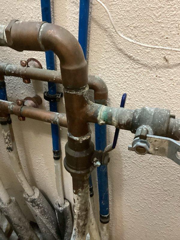 Responded to a mystery water leak in the laundry room and conducted a thorough inspection to identify the source. Located the leak at the main shut-off valve before the meter, which exhibited significant age-related deterioration, corrosion, and patina on the brass valve body. Documented the condition of the aging plumbing assembly with photographs and provided an estimate for main valve replacement, advising that city water shut-off coordination will be required to complete the repair work.