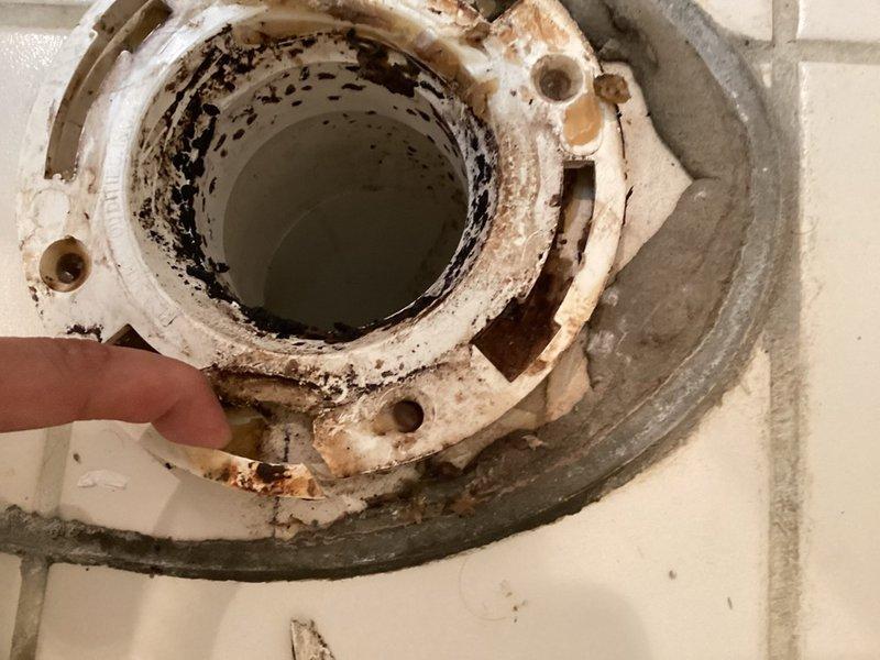 Responded to service call for toilet reseating evaluation. Upon arrival, removed toilet to inspect subfloor mounting system and discovered severely deteriorated toilet flange with visible cracking and extensive rust corrosion around mounting holes. The PVC flange exhibited structural damage and compromised integrity due to age and water exposure. Documented existing conditions through photography showing corroded flange, deteriorated mounting surface, and surrounding concrete substrate damage. Provided comprehensive estimates covering three options: repair and replacement of damaged toilet flange with reinstallation of existing toilet fixture, complete flange replacement with new toilet installation, and assessment of subfloor conditions requiring remediation prior to fixture reinstallation. Explained that proper flange replacement would require removal of damaged component, cleaning of drain pipe connection, installation of new flange assembly with secure fastening to subfloor, new wa