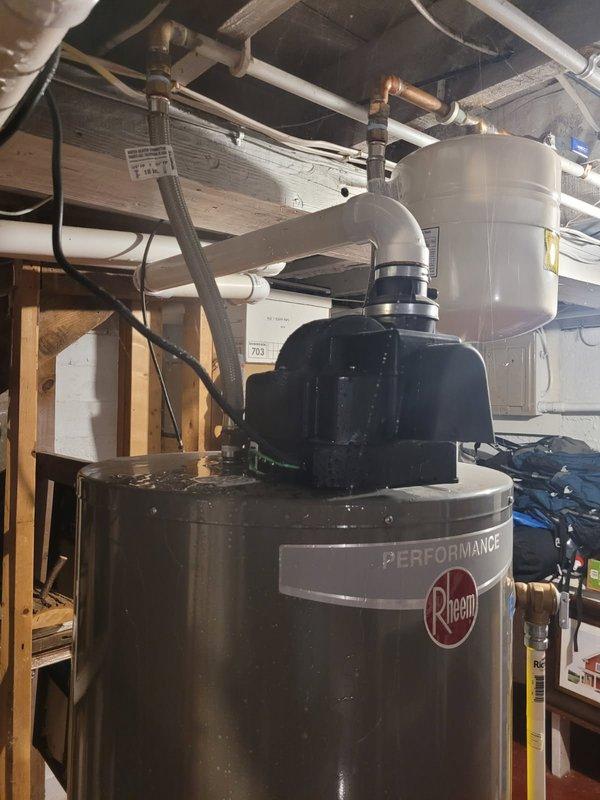 Responded to emergency call for water heater leaking and spraying steam from top of unit, causing basement flooding. Upon arrival, found 12-year-old Rheem Performance water heater with failed braided supply line as source of leak. Shut off water supply to house and turned off water heater to stop steam discharge. Removed and replaced defective braided supply line with new unit, restored water supply, and verified system operation with no leaks present.