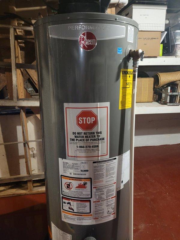 Responded to emergency call for water heater leaking and spraying steam from top of unit, causing basement flooding. Upon arrival, found 12-year-old Rheem Performance water heater with failed braided supply line as source of leak. Shut off water supply to house and turned off water heater to stop steam discharge. Removed and replaced defective braided supply line with new unit, restored water supply, and verified system operation with no leaks present.