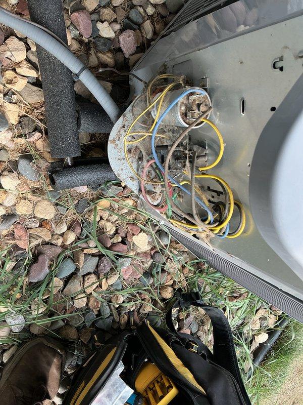 Responded to no-cool condition on 13-year-old residential air conditioning system where indoor unit circulated air but outdoor condenser unit failed to operate, producing only humming/hissing sound. Upon inspection, diagnosed failed dual capacitor testing significantly out of manufacturer specifications and condenser fan motor with visible oil leakage indicating bearing failure. Successfully replaced both dual run capacitor and condenser fan motor, restoring full system operation.