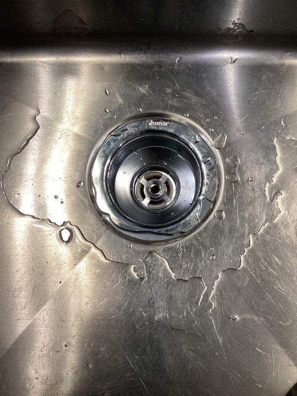 Responded to a water leak under the kitchen sink caused by a failed basket strainer. Removed the defective basket strainer assembly and installed a new Domar brand replacement unit, ensuring proper sealing to prevent further leakage. The new strainer was tested and confirmed to be functioning without any leaks.