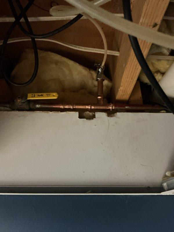 Responded to active water leak on refrigerator ice maker supply line. Upon arrival, found homeowner had already shut off water to the affected area. Inspection revealed a failed saddle valve on the copper waterline causing the leak. Removed the defective saddle valve and installed a new replacement valve to restore water supply to the ice maker. Tested the new installation for proper operation and verified no leaks were present. Photographed the completed work showing the new valve installation and surrounding plumbing connections. Additionally provided an estimate for water treatment services based on observations during the service call.