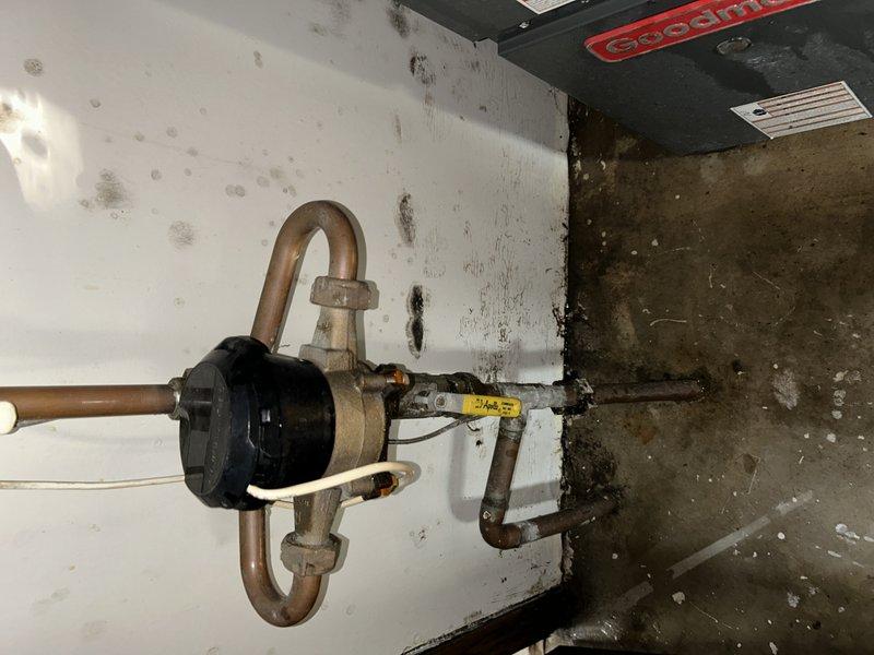 Responded to emergency water leak at duplex property where water supply had been shut off due to failed crimp joint from previous repair work. Upon arrival, identified pinhole leak originating from compromised solder fitting on copper piping near HVAC system connections. Removed defective crimp joint and solder fitting, prepared pipe ends, and installed new properly soldered connection to ensure watertight seal. Restored water supply and pressure-tested repair to verify no additional leaks present. Documented visible water damage on ceiling and wall surfaces near repair location, including staining and discoloration from previous leak events. Confirmed all plumbing connections secure and system operational before completing service.