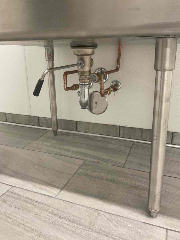 Conducted on-site evaluation for garbage disposal installation under commercial-grade stainless steel sink with drainboard. Assessed existing plumbing configuration including P-trap assembly, tailpiece connections, and supply line accessibility, then provided comprehensive installation estimates to customer.