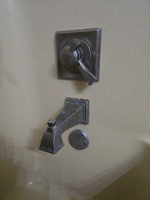 Installed customer-supplied trim kit for bathroom shower and tub fixture, including bronze finish control valve with square escutcheon plate and matching tub spout with diverter mechanism. Verified proper operation of temperature control and water flow through both shower and tub outlets, with all components functioning correctly upon completion.