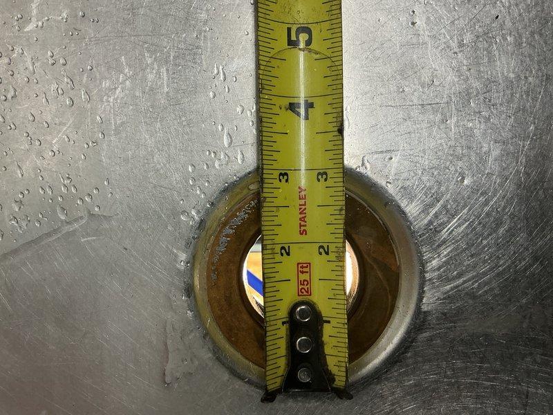 Responded to urgent leak under commercial kitchen sink that was causing water spillage onto the floor. Upon inspection, identified that the kitchen sink strainer had rotted out along with the connected piping leading to the T-fitting beneath the sink. Measured the existing sink strainer and determined it to be a non-standard 2-3/4 inch outside diameter size. Documented the deteriorated components with photographs showing the corroded strainer opening and measuring the dimensions for proper replacement parts. Submitted parts order request for the specialty-sized sink strainer and associated piping materials. Prepared estimate for the complete repair work, which will include removal of the failed strainer, installation of new strainer assembly, and replacement of deteriorated piping from the sink drain to the existing T-connection underneath the commercial sink.