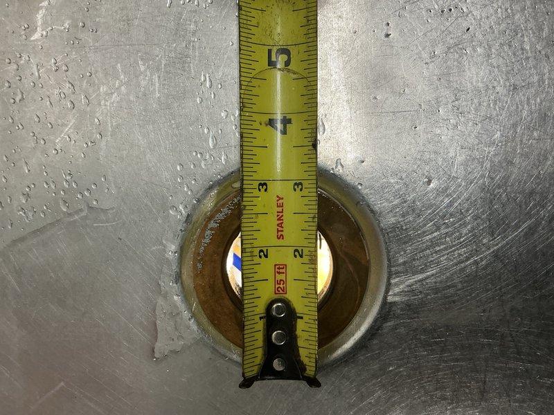 Responded to urgent leak under commercial kitchen sink that was causing water spillage onto the floor. Upon inspection, identified that the kitchen sink strainer had rotted out along with the connected piping leading to the T-fitting beneath the sink. Measured the existing sink strainer and determined it to be a non-standard 2-3/4 inch outside diameter size. Documented the deteriorated components with photographs showing the corroded strainer opening and measuring the dimensions for proper replacement parts. Submitted parts order request for the specialty-sized sink strainer and associated piping materials. Prepared estimate for the complete repair work, which will include removal of the failed strainer, installation of new strainer assembly, and replacement of deteriorated piping from the sink drain to the existing T-connection underneath the commercial sink.