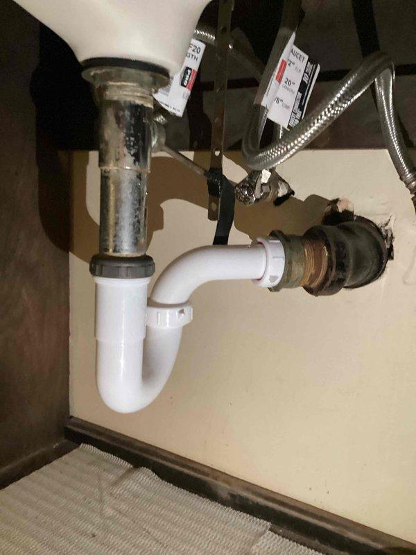 Responded to a water leak under the bathroom sink caused by a corroded P-trap with a pinhole leak. The homeowner had already shut off the water supply to the sink to prevent further water damage. Upon inspection, confirmed the white P-trap had rusted through and was actively leaking. Removed the deteriorated P-trap assembly and installed a new chrome-plated P-trap with proper sealing connections. Verified all drain connections were secure and tested the system for proper drainage and leak-free operation. Restored water supply to the sink and confirmed no additional leaks were present in the supply lines or shut-off valves.